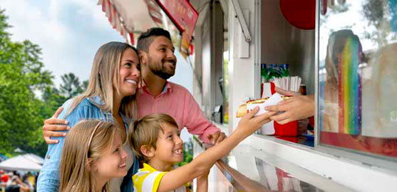 a smiling family recieves food at a food truck.