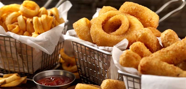 Metal baskets filled with curly fries, onion rings, and mozzarella sticks served with ketchup.