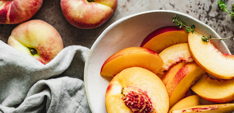 Peaches in a bowl and on a table.