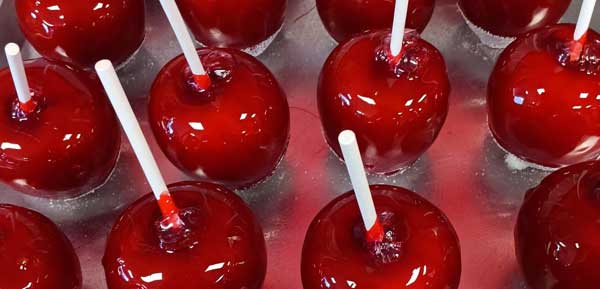 bright red candied apples lined up on a metal tray