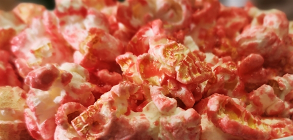 Close-up of holiday popcorn coated in a red and white candy cane glaze, showcasing a festive, sweet, and crunchy texture.