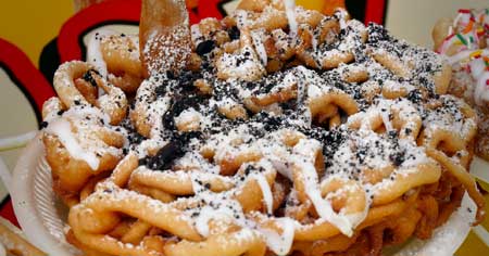 Regular Funnel cake topped with Oreo cookie pieces and whip cream topping.