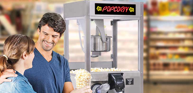 A couple smiles at each othe after getting popcorn from a popcorn vending machine
