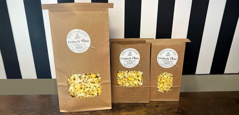 popcorn packaged in brown paper bags with black and white striped wall in background