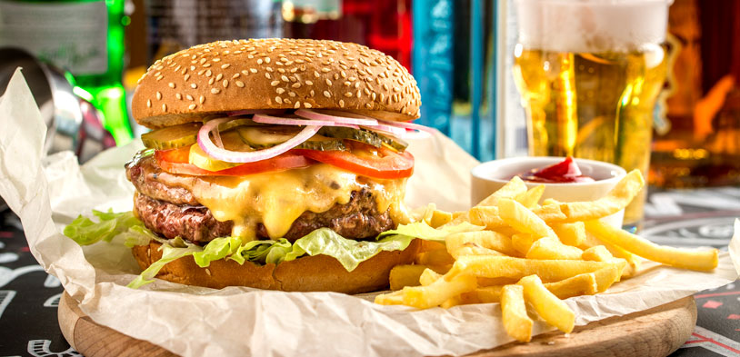 a fully loaded burger with fries on a sports themed table