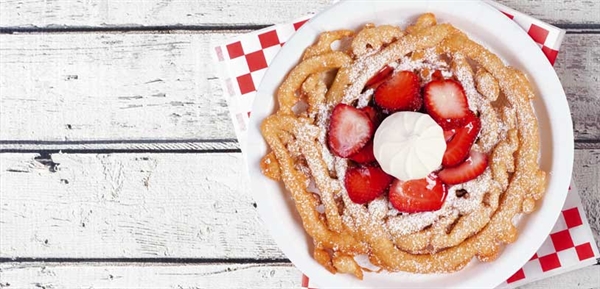 funnel cake with fruit on top along with crème on a white wooden table