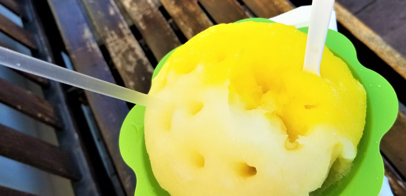 a person holds a green cup filled with shaved ice