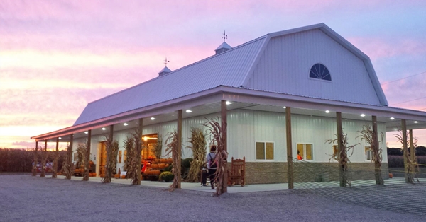 Niederman Farm barn decorated with cornstalks at sunset, featuring a pastel sky and festive autumn atmosphere.