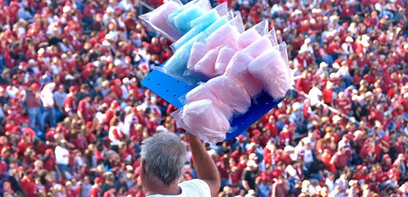 Man selling cotton candy in stadium in pre-packaged bags.