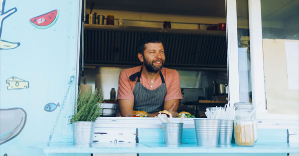 man smiles standing in his food truck.