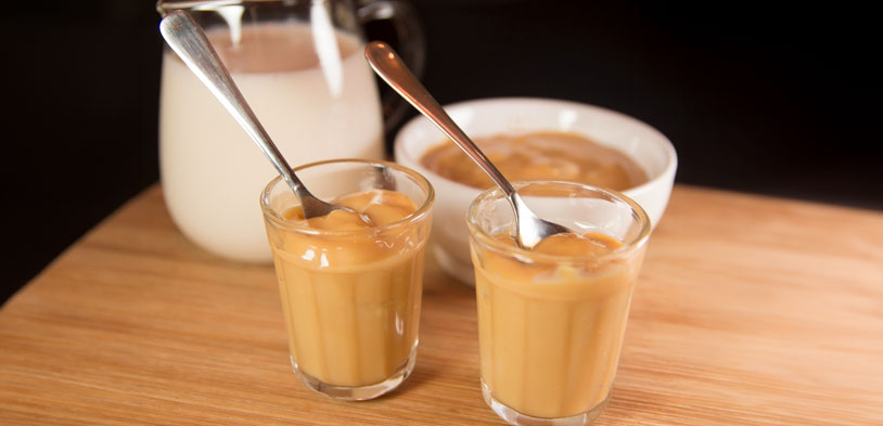 Milk and Caramel with glasses being mixed on table.
