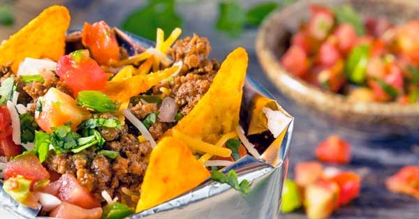 Walking Tacos held in hand in a silver foil pouch