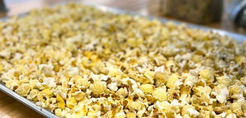 Yellow cole market gourmet popcorn on a silver baking platter.