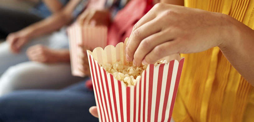 people eating popcorn on a couch from buckets