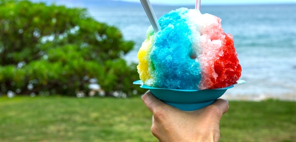 A person holds a rainbow pop style shaved ice cup