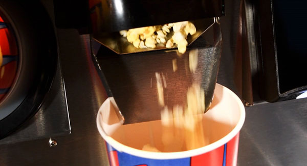 Popcorn vending machine dispensing popcorn into paper cup