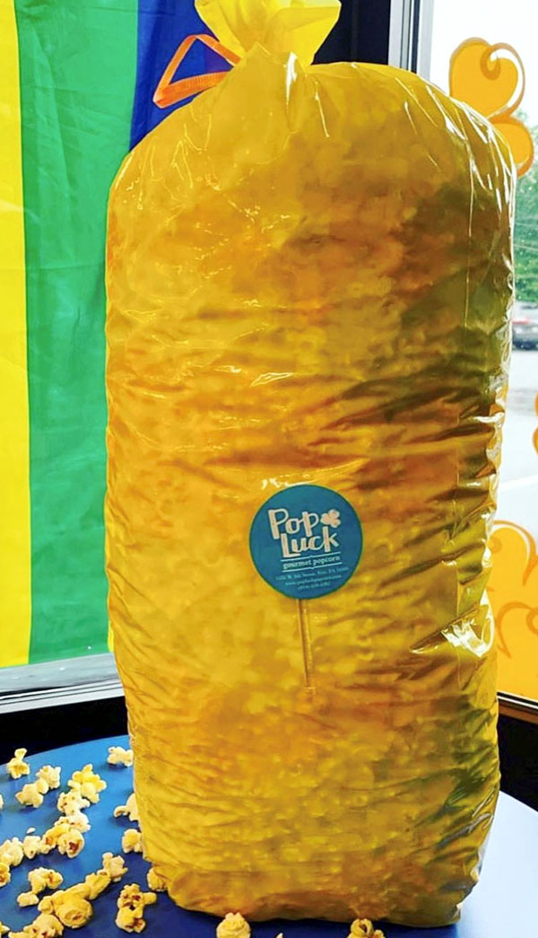 A yellow plastic bag of PopLuck's branded popcorn on a table.