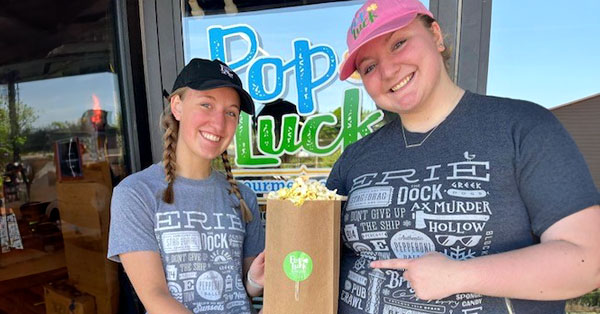 Two women in front of store holding a bag of popcorn.