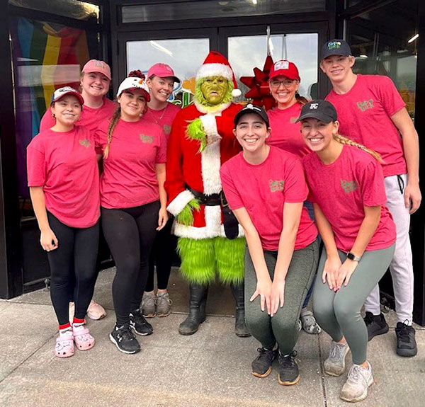 PopLuck staff in front of building with the Grinch during Christmas.