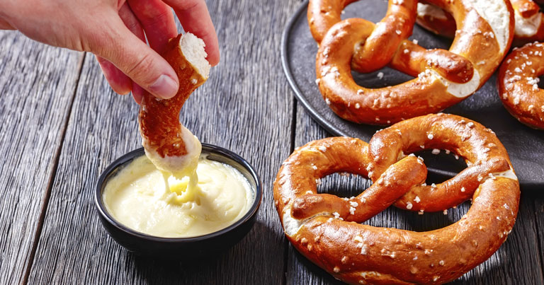 Pretzels in the form of knot with cheese sauce