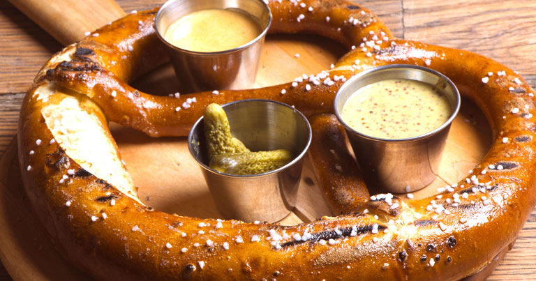 Freshly baked soft pretzel with coarse salt on wooden cutting board