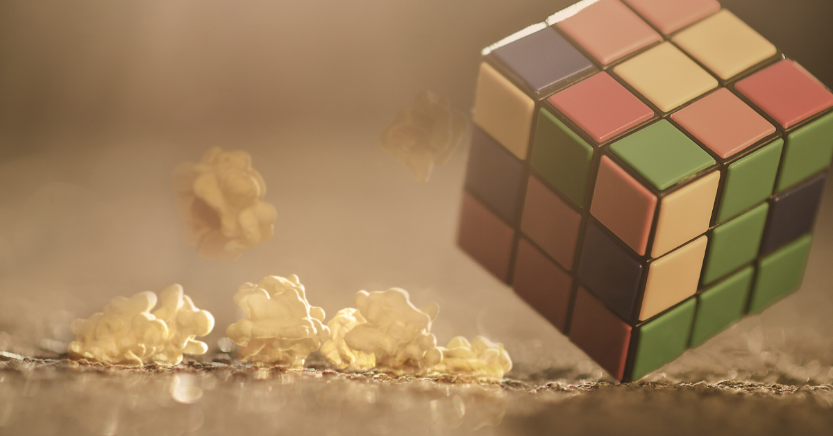 angled Rubiks cube with pieces of popcorn sitting on surface in warm light angled Rubiks cube with pieces of popcorn sitting on surface in warm light