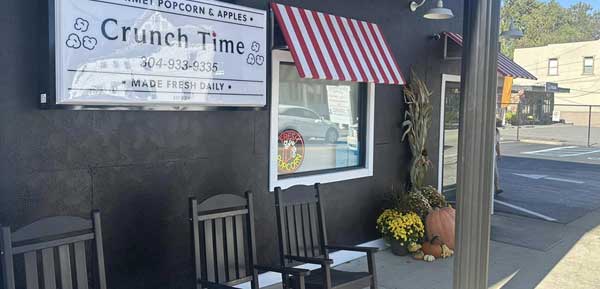 Exterior view of Crunch Time shop featuring rocking chairs, fall decorations, and a sign for 168飞艇历史记录查询结果 gourmet popcorn and apples.