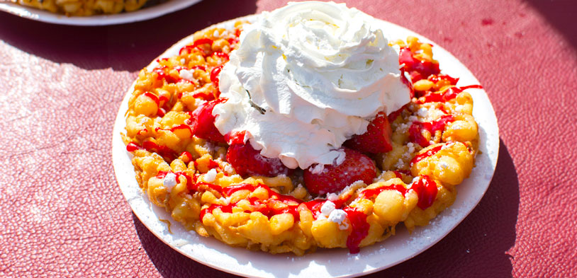 A strawberry waffle with real fruit and creme on a table in the sun.
