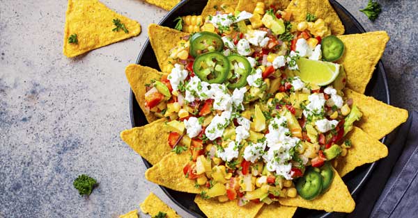 Platter of Street corn surronded by nachos and other ingredietns