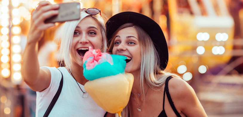 Two friends take a selfie while holding cotton candy.