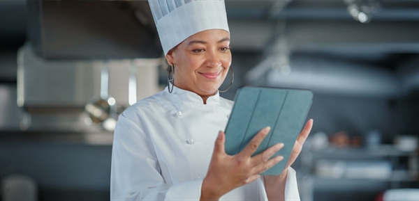 A female chef holding an tablet in a kitchen