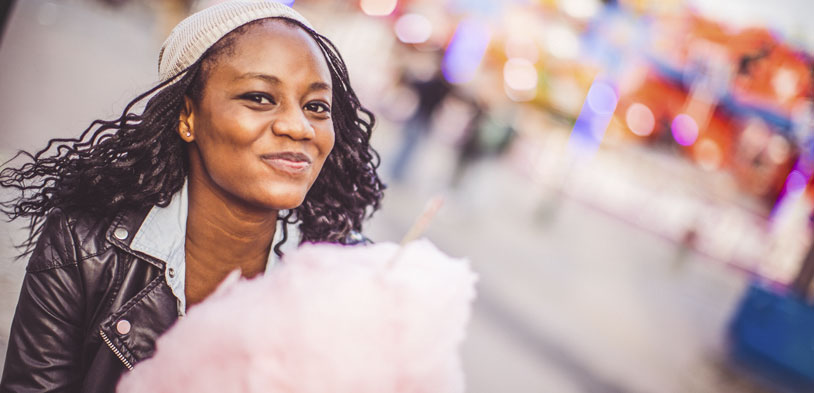 woman smiling as she enjoys her cotton candy