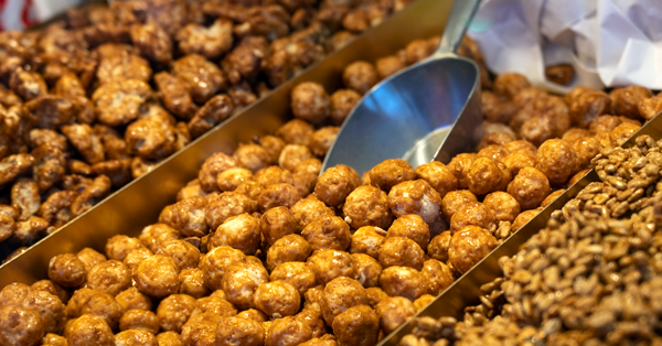 a metal serving scoop next to a variety of frosted nuts