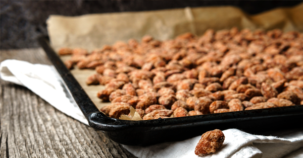 black baking sheet full of frosted nuts fresh from the oven