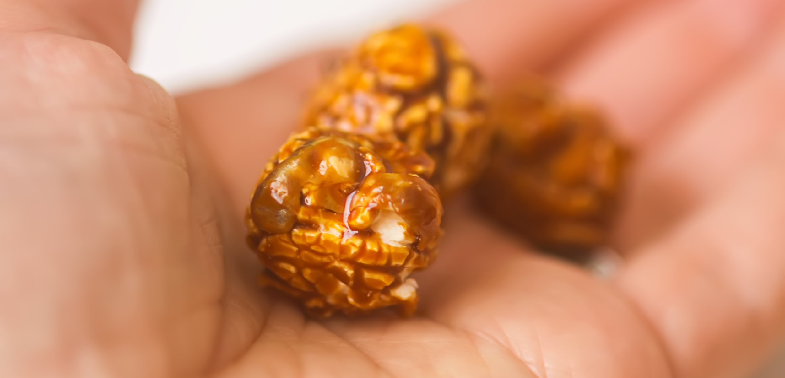 Hand holding pieces of caramel corn with rich coating Hand holding pieces of caramel corn with rich coating