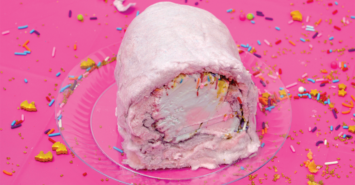 pink cotton candy burrito with ice cream filling on a clear plastic plate and hot pink background with scattered rainbow sprinkles
