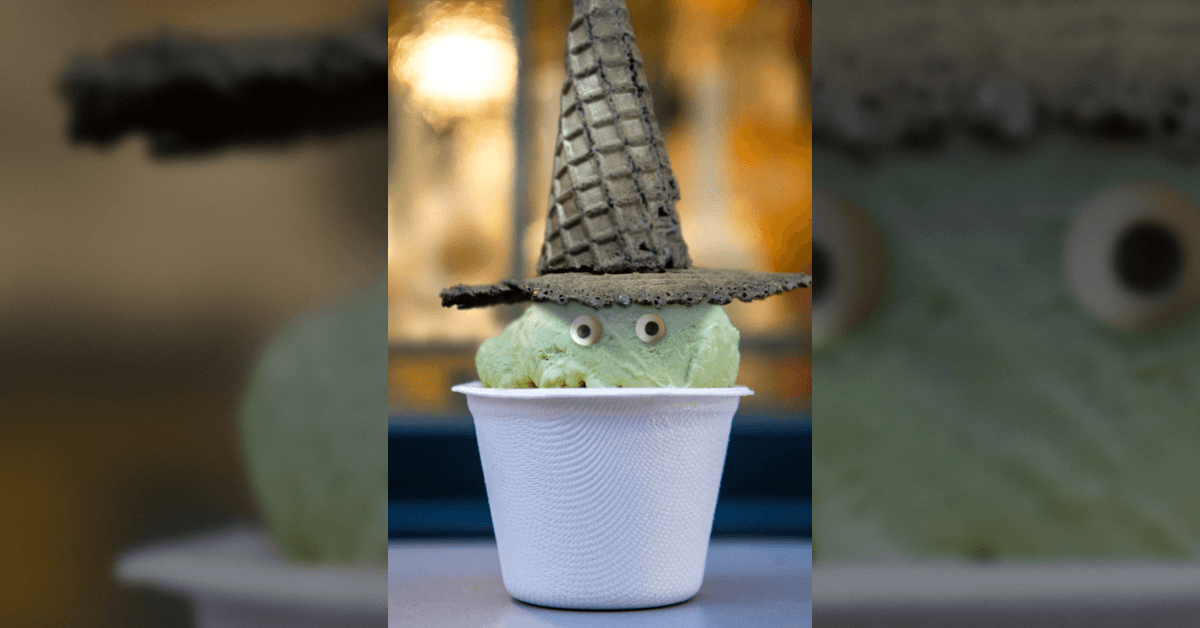 creative witch with black waffle cone hat, green ice cream, and candy eyes in a white cup