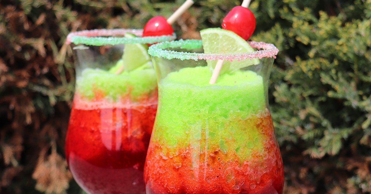 red and lime green cherry limeade frozen slush beverage in glass with cherry and lime flossugar sugar garnished with a cherry