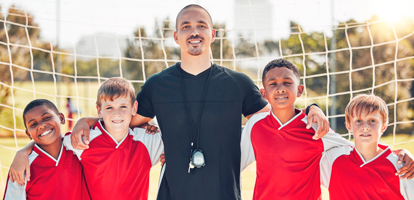 Soccer team with coach in front of soccer net