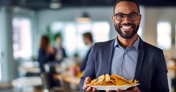a black male smiles at camera while holding his plate of nachos