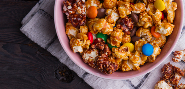 candy and popcorn mixed together in a bowl on a table