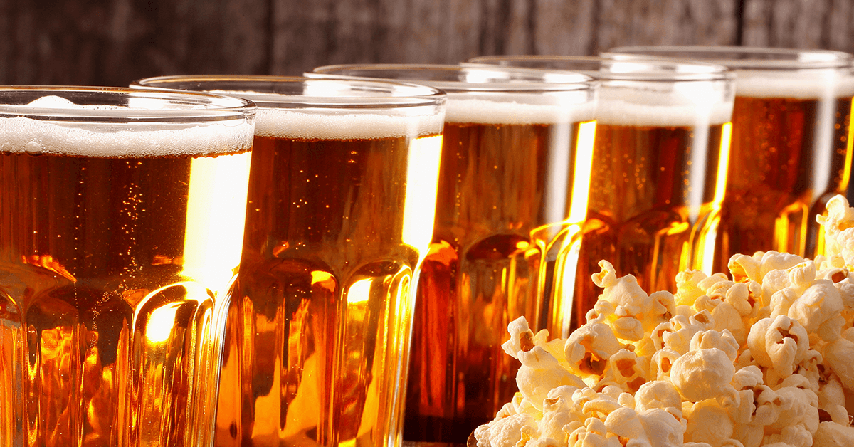a row of light draft beers with buttered popcorn to the side a row of light draft beers with buttered popcorn to the side
