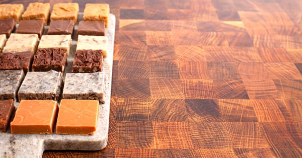 several varities of fudge lay on a cutting board sliced up and ready to serve