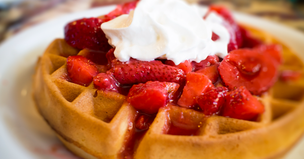 a waffle with strawberries and cream on top